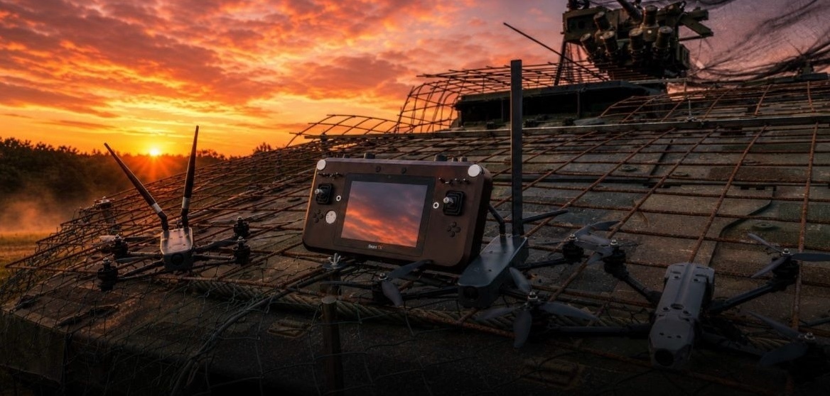 BeastTX ground control station with FPV aircraft on a camouflage-netted armored vehicle at dusk